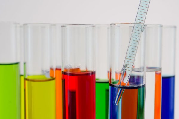 Close-up of colorful test tubes with a glass pipette in a laboratory setting.