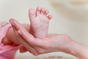 Tender moment showing a baby's bare foot cradled in an adult's hand, symbolizing care and love.