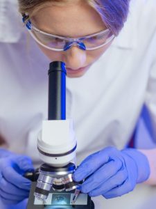 A female scientist examining a slide through a microscope in a laboratory.